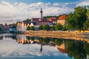 Die Altstadt von Landsberg am Lech spiegelt sich in der glatten Oberlfäche des Lechs
