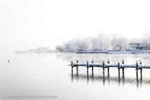 Winterliche Aufnahme von einem verschneiten Steg im Ammersee
