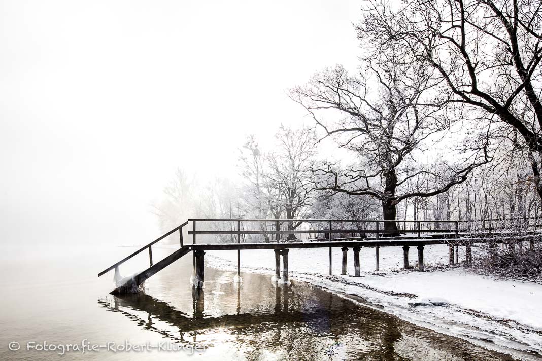 Ein Badesteg am Ammersee im Winter bei Schnee in Utting am Ammersee