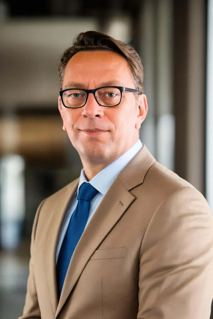 Stefan Rübener im beigen Anzug mit blauer Krawatte