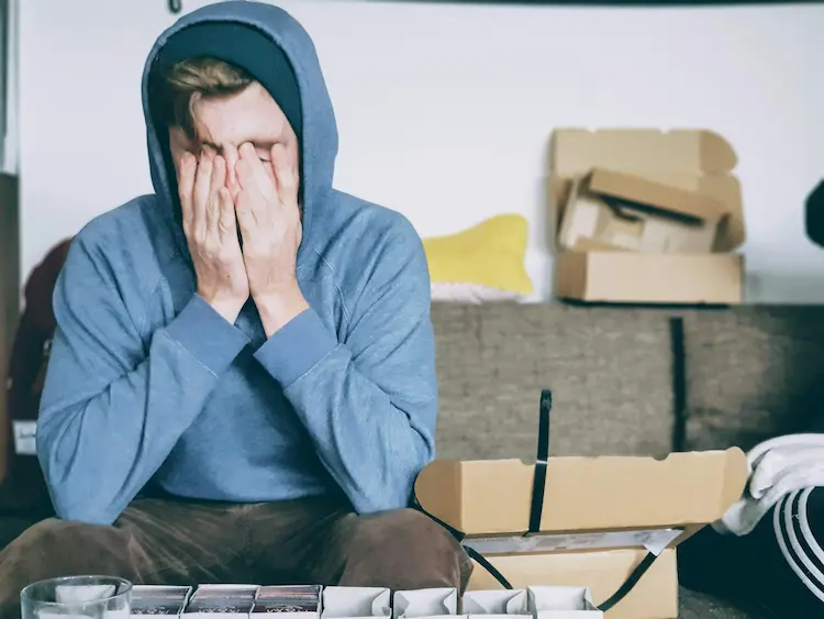 A man sitting and covering his face with his hands.