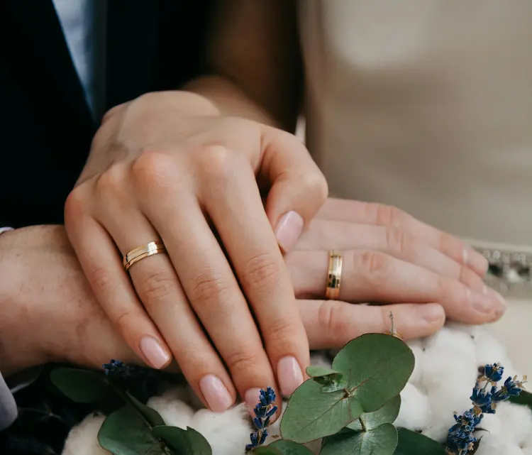 A couple's hands with both their wedding rings on their fingers.