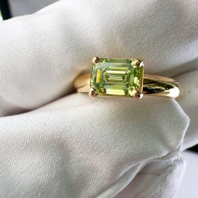 Ashes to Diamonds - A Hand is holding a beautiful golden ring With a Green Diamond