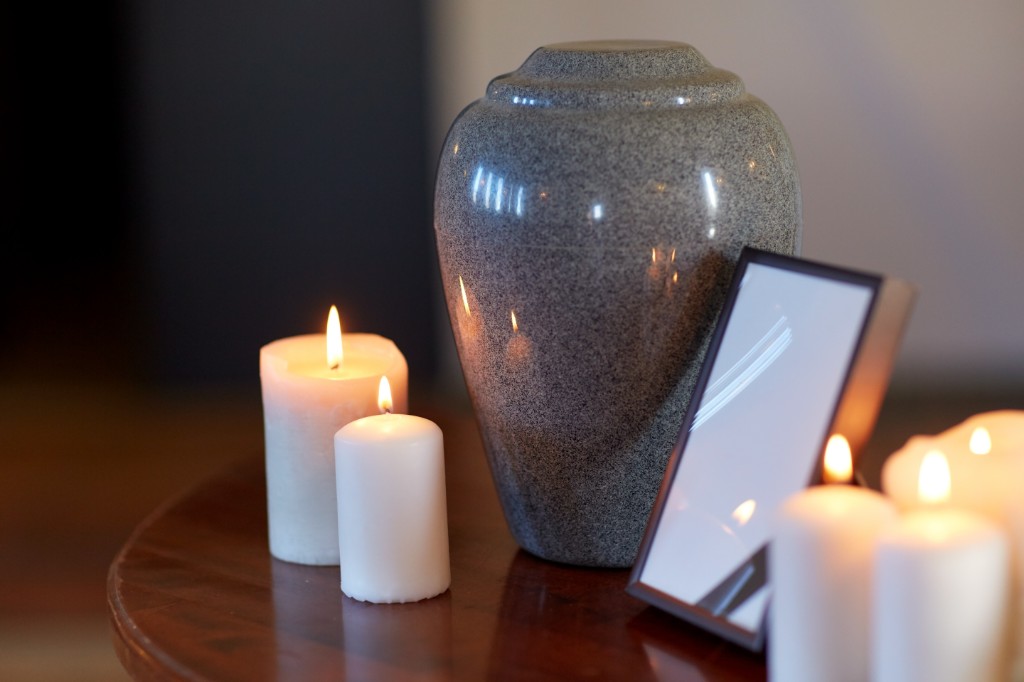 A cremation urn between lit candles