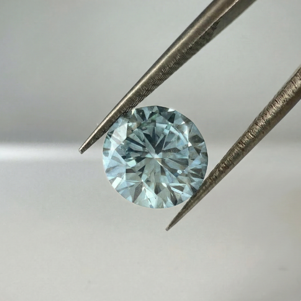 Loose round brilliant memorial diamond held in tweezers for inspection