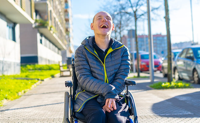 Jugendlicher mit Rollstuhl auf Straße Lachend 650x400 web