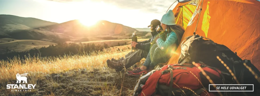 To personer der er på campingtur i telt, der ser solopgangen