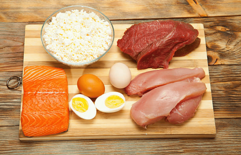 A table with many protein-rich foods: red meat, chicken, salmon and eggs.