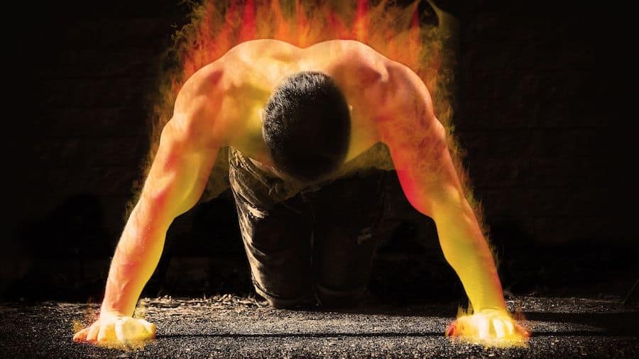 A shirtless man on his knees with his hands on the ground, his body on fire to symbolize the fact that he has trained for muscular failure.