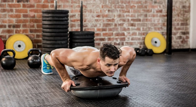 A sportsman does push-ups on a BOSU.