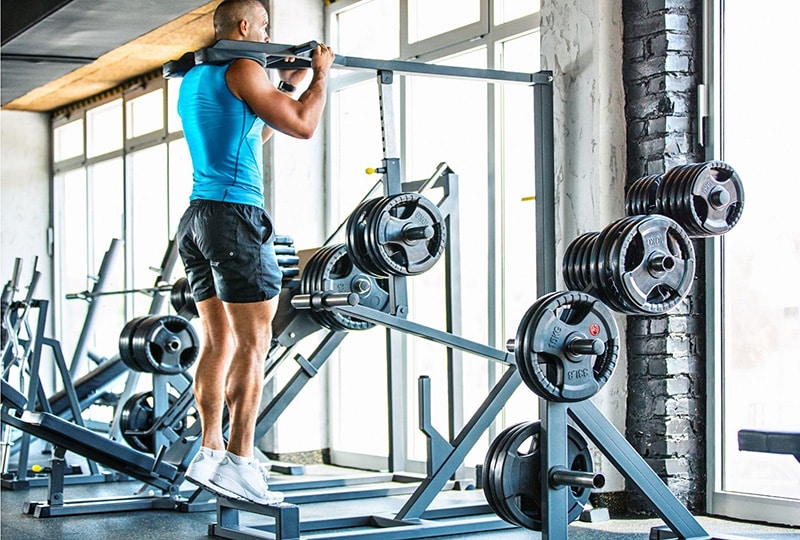 Un homme fait des élévations de mollets à la salle de musculation.