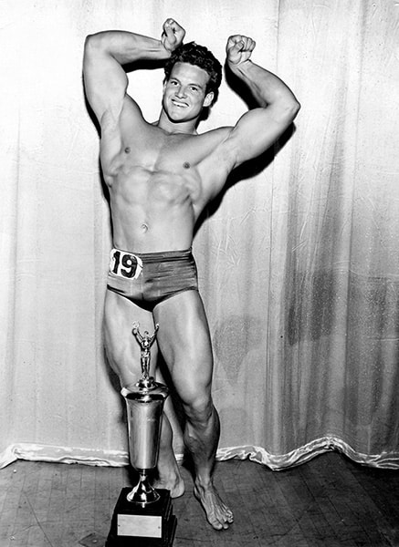 Steve Reeves poses after winning a bodybuilding competition.