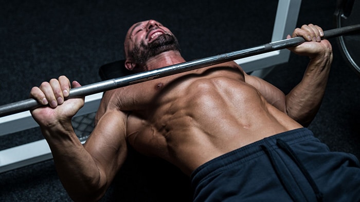 A weightlifter performs the bench press exercise.