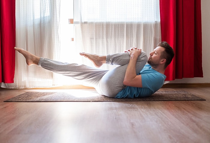 Un homme s'étire le psoas allongé sur le sol.