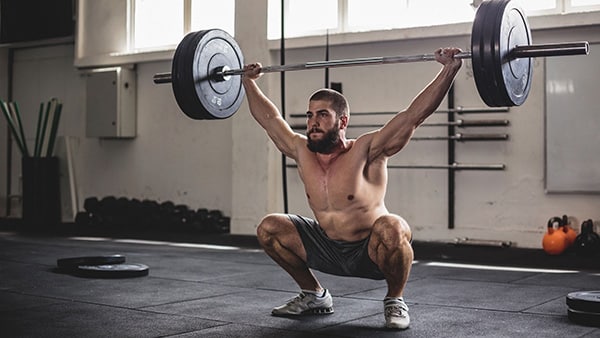 A weightlifter performs a snatch with a barbell.