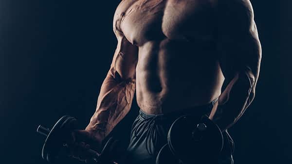 A muscular man works out with dumbbells.