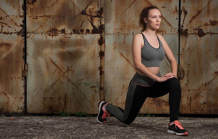 A woman performs the basic lunge stretching exercise.