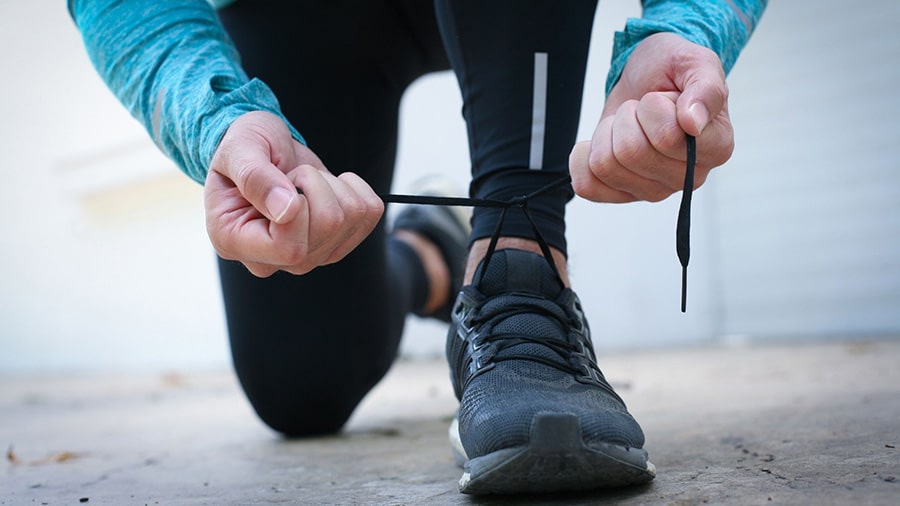 A sport makes the laces of his running shoes.