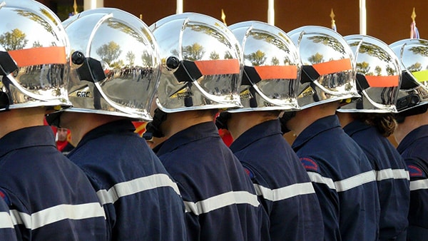 Firemen in line with their helmets on their heads.