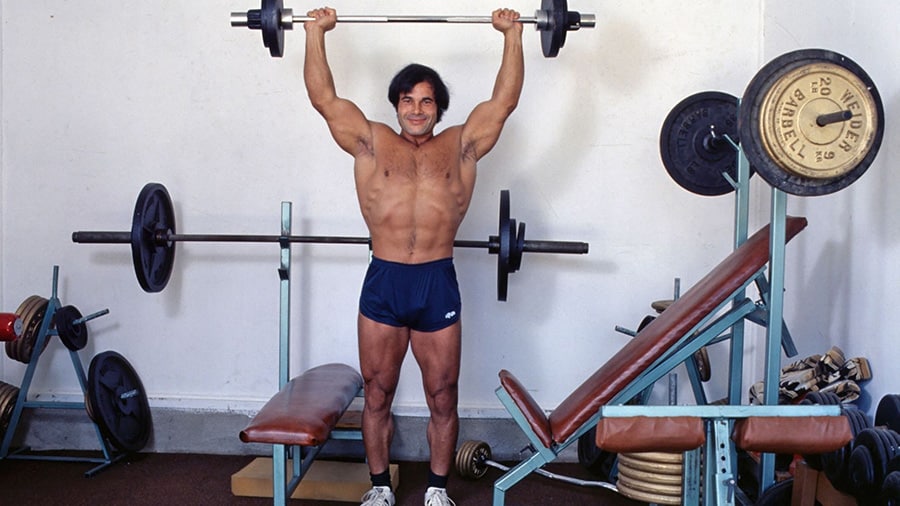 L'athlète Franco Columbu en train de faire l'exercice de musculation du développé épaules.