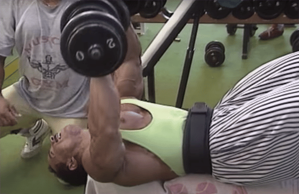 Mohamed Benaziza en train de faire du développé couché aux haltères à la salle de musculation.