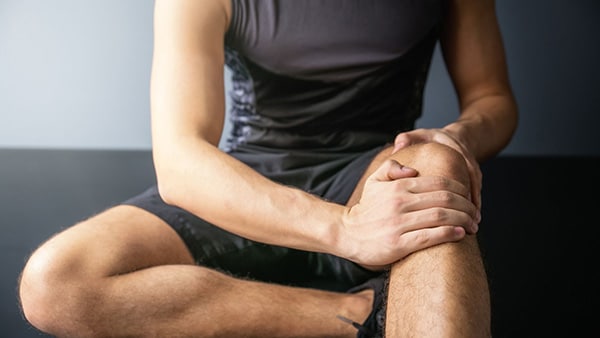 A man holds his left knee after an injury.