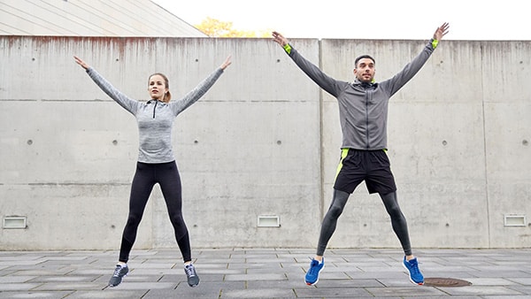 A man and a woman doing jumping jacks.