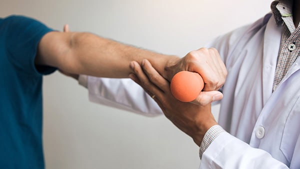 A man performs a rehabilitation exercise at a physical therapist after a rotator cuff injury.