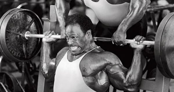 Lee Haney lifts a weight bar during a workout at the gym.