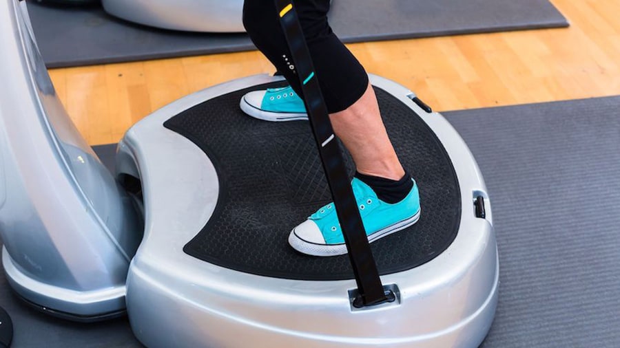 A person wearing sports shoes stands on a vibrating platform.