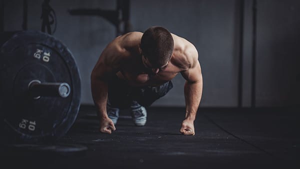 Un homme fait des pompes sur les poings dans une salle de musculation.