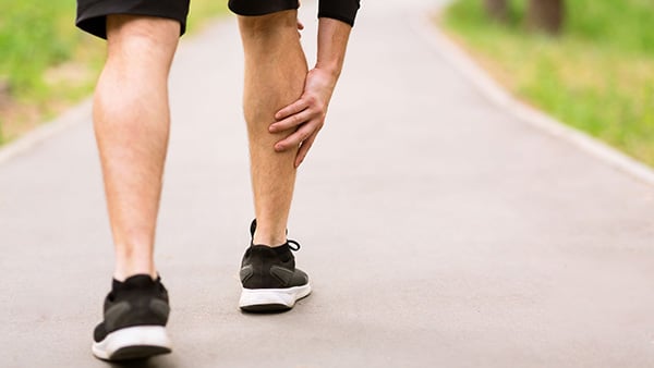 A sportsman holds his right calf after a pain appears.