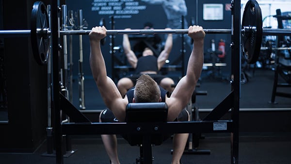 A man does a bench press in a weight room.