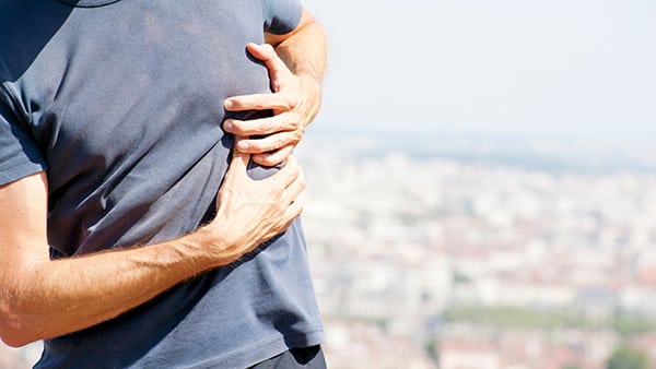 A man suffering from a stitch in his side stands under the ribs.