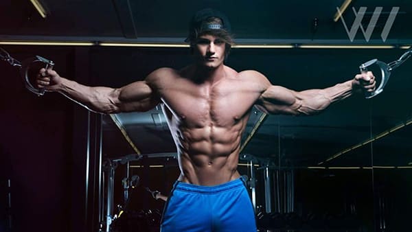 Jeff Seid shirtless performing a weight training exercise at the gym.