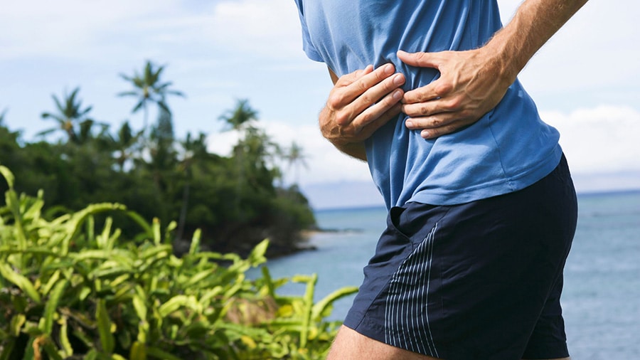 A runner has his hands resting on his abdomen following a side stitch.