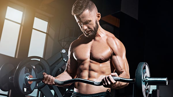 A shirtless man, muscles and abs protruding, is doing a biceps workout.