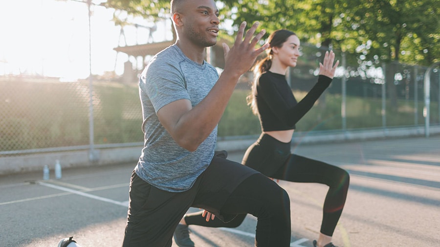 Un homme et une femme effectuent l'exercice des fentes dans le cadre d'un programme de remise en forme.