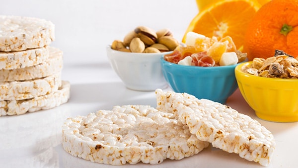 Une collation saine avec des galettes de riz, des oranges et des fruits secs.