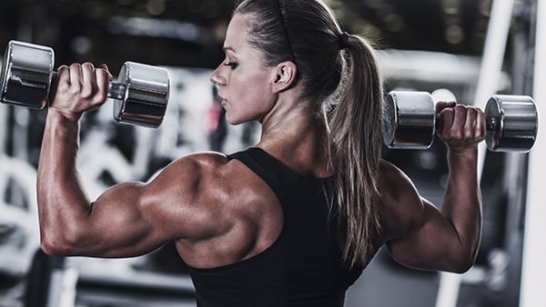 A woman performs a weight training exercise with dumbbells.