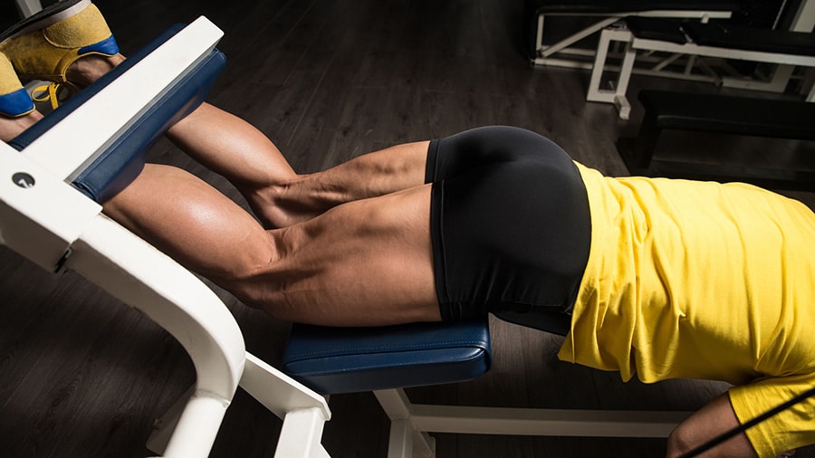 A man in shorts performs a leg curl, a strength training exercise for the hamstrings.