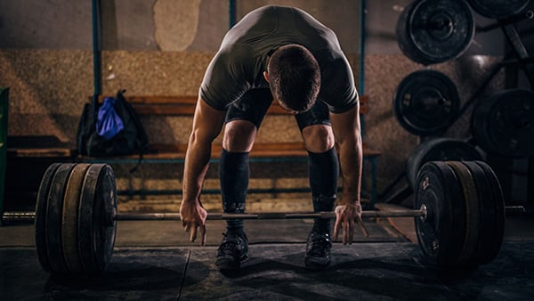 A man is training in a gym and is about to perform the deadlift.