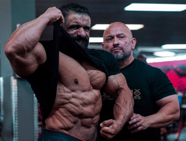 At left, Hadi Choopan lifts his shirt and shows off his abs with trainer Hany Rambod, right.