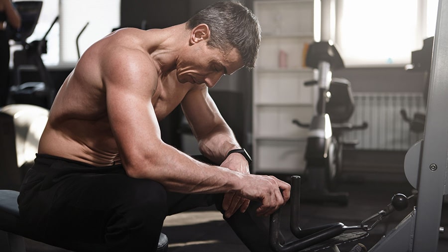 Un homme torse nu qui semble fatigué dans une salle de musculation.