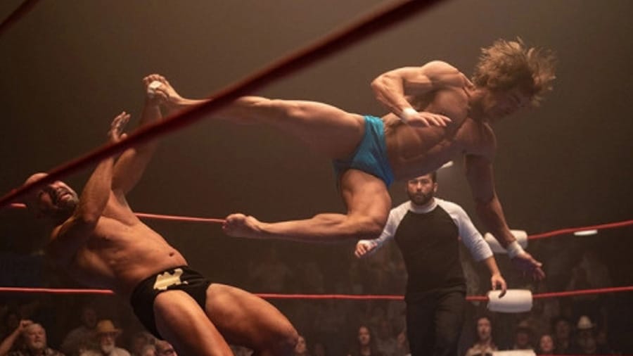 A photo from the movie The Iron Claw, in which Zac Efron plays a wrestler. In the photo, the actor performs an aerial wrestling hold on a ring and puts his opponent on the ground.