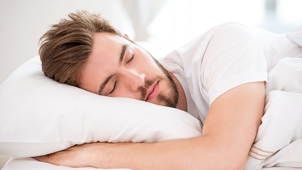 Un homme qui dort dans un lit pour illustrer les bienfaits de l'ashwagandha en musculation.