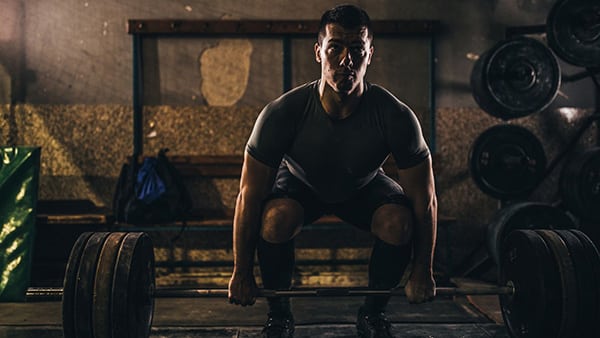 A man performs the deadlift in a gym.