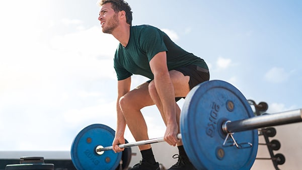 An athletic man performs the deadlift to work his lower back.