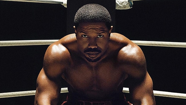 Michael B. Jordan as Adonis Creed, sitting in the corner of the ring during a boxing match.