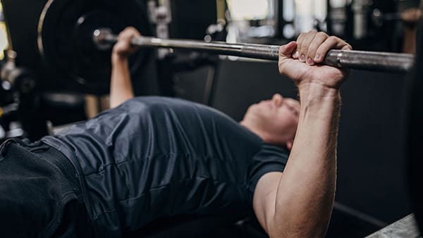 An athlete in a gym performs the bench press exercise for pectoral muscles.